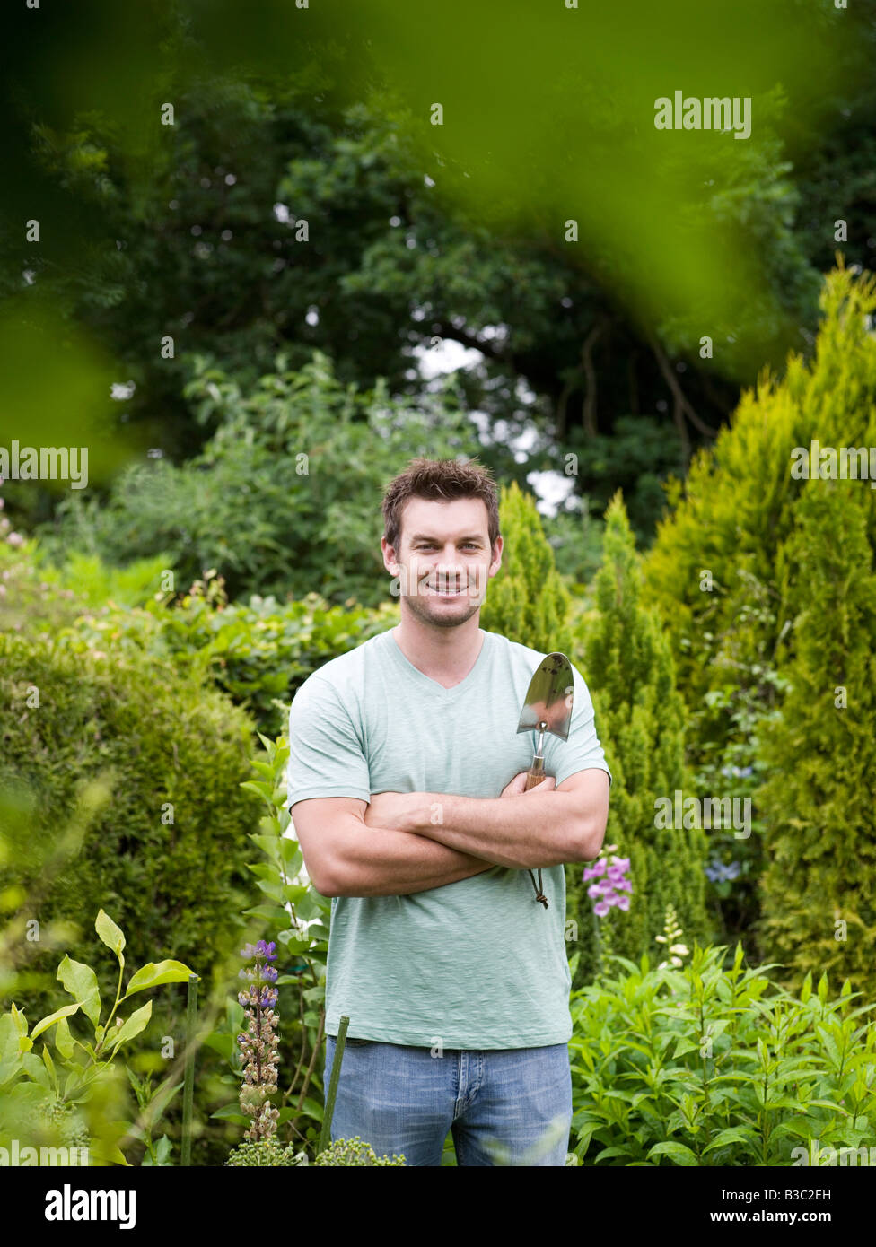 a-man-standing-in-a-garden-with-a-trowel-B3C2EH.jpg